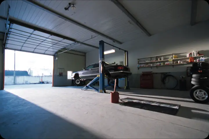 A repair bay with a car raised on a two-post lift.