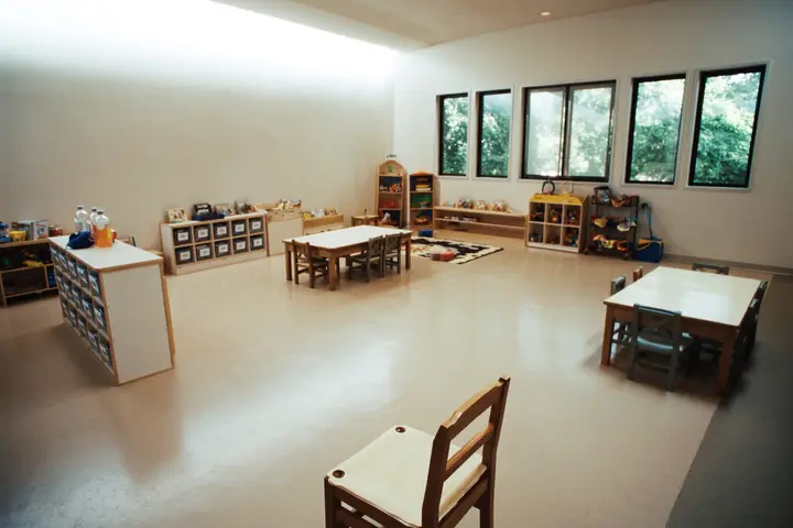 A daycare room with low tables and cubby shelving.
