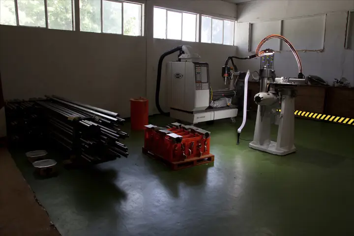 A small machine shop floor with bar stock and a CNC machine.