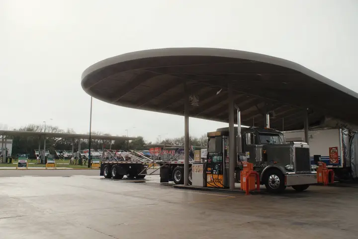 A tractor unit parked at a truck stop fuel island.